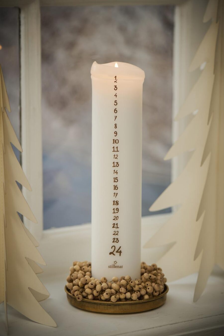 Objets de Bibi - Ib Laursen Una ghirlanda con perline in legno realizzata a mano a decorare una bellissima candela dell'avvento